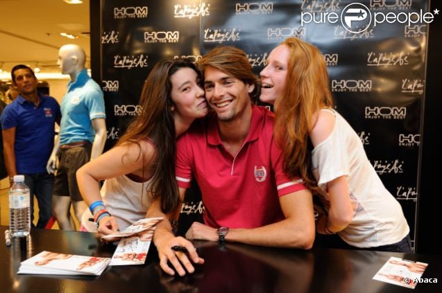 Camille Lacourt pose en compagnie de deux de ses fans aux Galeries Lafayette, à Paris, samedi 1er septembre 2012.