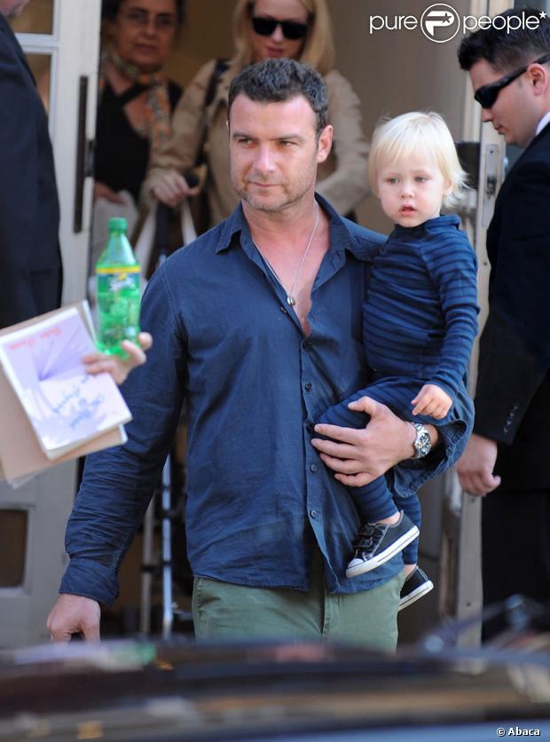 Naomi Watts (en arrière-plan) et Liev Schreiber portant leur fils aîné Alexander sortant de leur appartement à New York le 10 juillet 2009