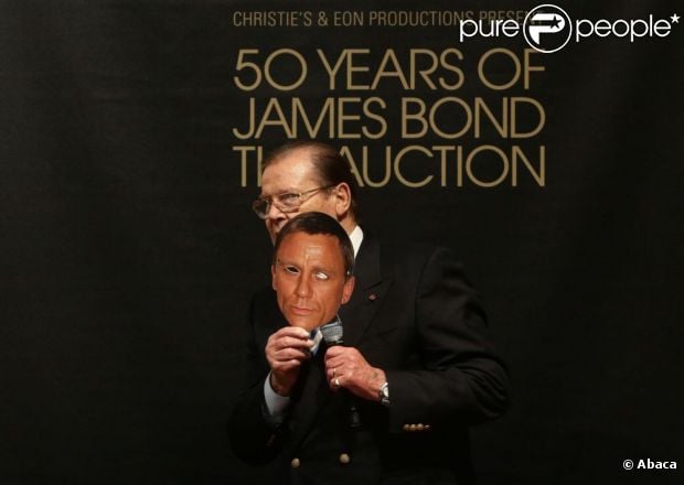 Sir Roger Moore s'éclate avec un masque de Daniel Craig ! Vente aux enchères d'objets de la saga James Bond donnés par les acteurs de la franchise, chez Christie's, à Londres, le 5 octobre 2012