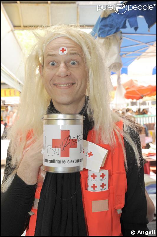 Alain Bouzigues a remplacé sa machine à café par un tirelire la Croix-Rouge. Mais en blonde, il ne doit pas faire la différence ! Après ses t-shirts aussi moulants que fluos, porter la perruque blonde pour Alain, c'est un jeu d'enfant !  
