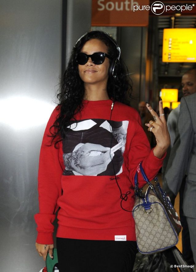 Rihanna habillée d'un pull Diamond Supply Co., lance un "Deuces" aux photographes à son arrivée à l'aéroport d'Heathrow. Londres, le 27 août 2012.