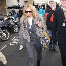 Kate Moss quitte les studios de la radio BBC Radio 1, habillée d'une veste en fourrure, d'une combinaison grise et de bottines Azzedine Alaïa. Londres, le 14 mars 2013.