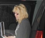 Courtney Love arrive avec ses chiens à Miami Beach et tente de se cacher derrière son ordinateur portable en juillet 2010 