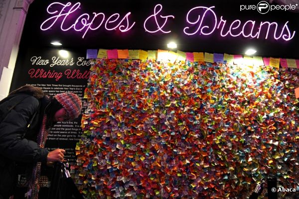 Meilleurs voeux de New York ! Une jeune femme écrit son voeu sur un morceau de confetti qui rejoint tous ceux déjà affichés sur un mur à Times Square.  