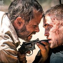 Guy Pearce menace Robert Pattinson pour la première image de <em>The Rover</em>, révélée par <em>Entertainment Weekly</em>.