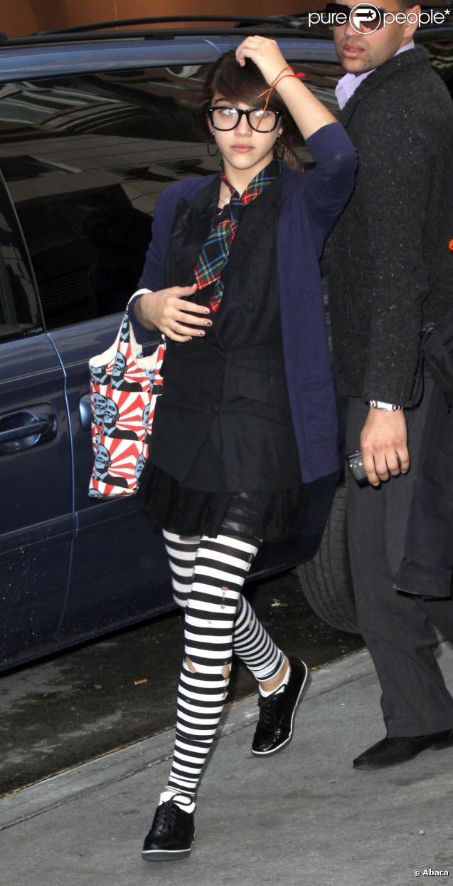 Lourdes porte un legging (légèrement troué) façon Beetlejuice, avec de jolies Derby aux pieds, une cravate en tartan, et des maxy Wayfarer sur le nez. Le mélange des genres, elle adore ! 