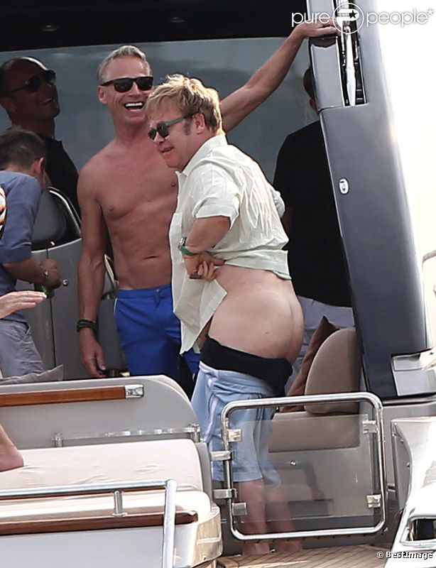 Elton John, entouré d'amis sur un yacht, montre ses fesses aux photographes au large de St-Tropez, le lundi 13 août 2012.
