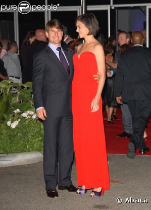 Fan absolue des Louboutins (les fameuses chaussures à la semelle rouge), Katie les accessoirise avec une sublime robe de soirée du même colori. Tom est trop sobre, à côté ! (fête des Beckham à LA - 22 juillet 2007)