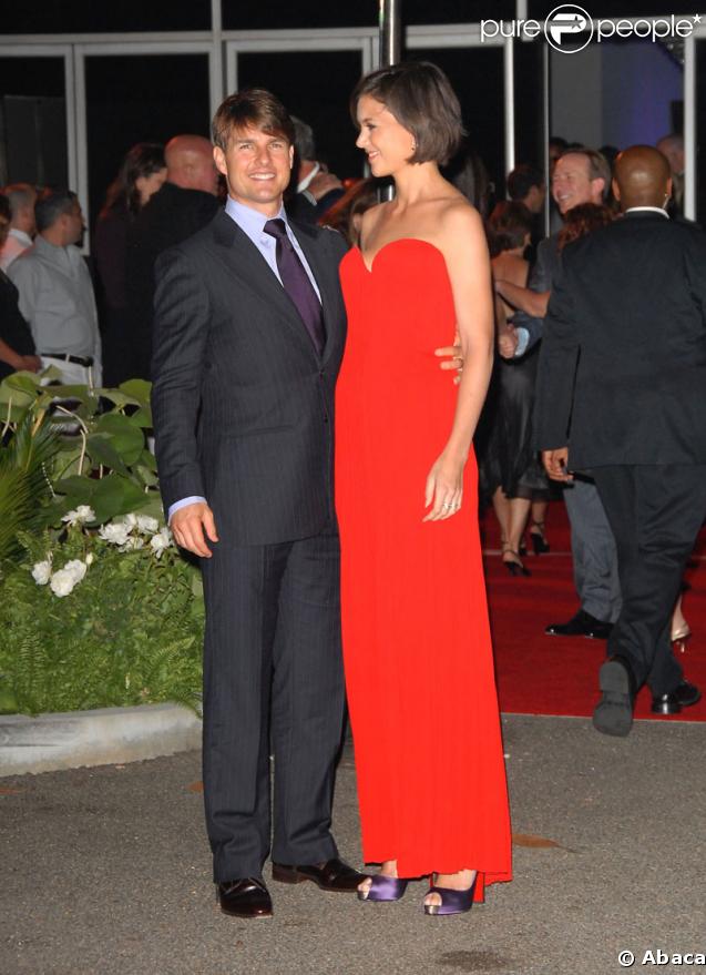 Fan absolue des Louboutins (les fameuses chaussures à la semelle rouge), Katie les accessoirise avec une sublime robe de soirée du même colori. Tom est trop sobre, à côté ! (fête des Beckham à LA - 22 juillet 2007) 
