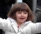 Suri, ravie, se balance aux bras de ses parents à New-York, en décembre 2008. Doudoune blanche assortie aux collants et aux ballerines, pas de fashion faux-pas pour miss Cruise, accompagnée de sa nouvelle amie la girafe ! 