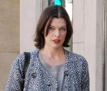  Ballerines aux pieds, collants opaques, robe en laine grise ceinturée, et manteau psyché assorti,le top model Milla Jovovich est à tomber. 
