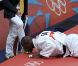 Teddy Riner embrasse les chaussures en or de son coach Benoit Campargue après avoir décroché l'or olympique le 3 août 2012 à Londres