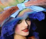 Zoom sur un modèle du défilé printemps-été 2009 de John Galliano, dans une tenue vert pomme et chapeauté d'une création multicolore. 