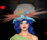 Un mannequin du défilé printemps-été 2009 de John Galliano s'avance sur le podium dans une tenue flashy composée d'un top destructuré vert pomme assorti d'une jupe orangée. 