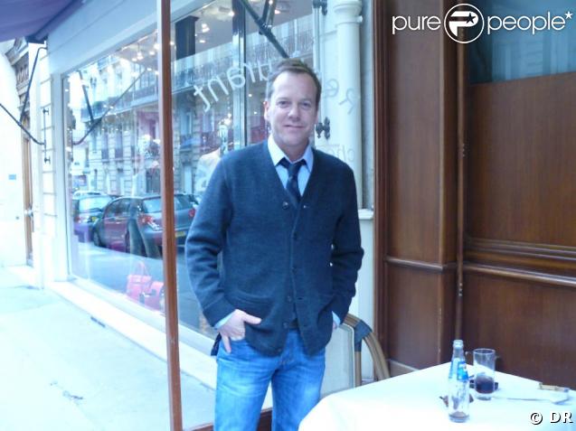 Kiefer Sutherland à la terrasse d'un restaurant parisien, seul et souriant