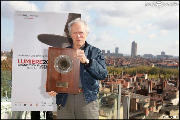 Clint Eastwood pose avec son prix devant l'affiche de la manifestation, à l'occasion de la clôture du Festival Lumière de Lyon, le 18 octobre 2009 !