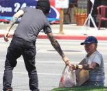 Pete Wentz offre un sac de denrées alimentaires à un homme dans le besoin, à Los Angeles, dimanche 22 août.