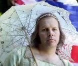  C'est vêtu d'une majestueuse robe blanche, coiffé d'un diadème et sous une ombrelle en dentelle que Philippe Katerine incarne  La reine d'Angleterre . Un hommage distingué qui tombe à pic pour le mariage princier. 