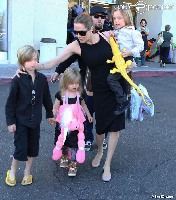 Angelina Jolie emmène trois de ses enfants faire du shopping pour Halloween le 28 octobre 2012 à Sherman Oaks en Californie dans le magasin Party City : elle porte dans ses bras son fils Knox, tandis que Shiloh, l'aînée, tient la main de la petite Vivienne