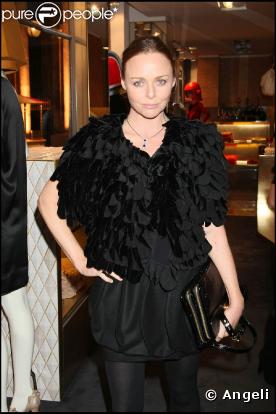 La jolie Stella prend la posedans son superbe ensemble noir, petite robe courte bouffante et gilet de pétales