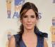 Sandra Bullock habille ses jolies jambes de collants opaques noirs pour compléter sa robe brillante.