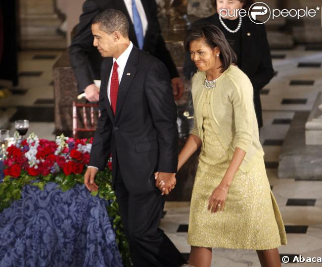 Pour réhausser, d'une petite touche classique, sa jolie robe imaginée par Isabel Toledo, Michelle Obama portait un gilet boutonné d'un bijou de broche, le 20 janvier 2009. 
