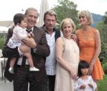 Joy dans les bras de Jean-Claude Darmon, Johnny Hallyday, Hélène Darroze, Jade et Laeticia Hallyday lors de la journée de baptême de Joy à Gstaad en Suisse le 5 juillet 2009