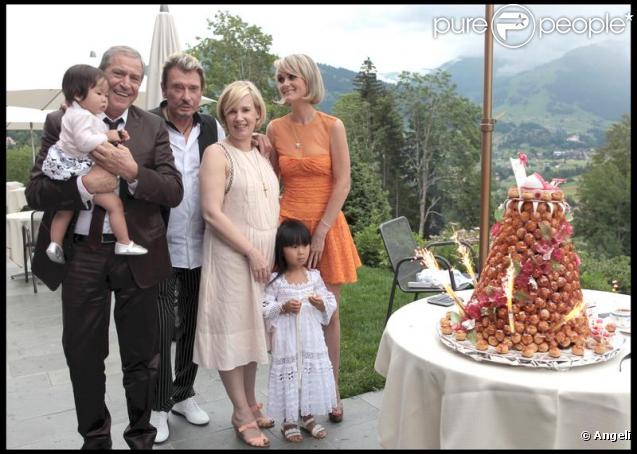 Joy dans les bras de Jean-Claude Darmon, Johnny Hallyday, Hélène Darroze, Jade et Laeticia Hallyday lors de la journée de baptême de Joy à Gstaad en Suisse le 5 juillet 2009