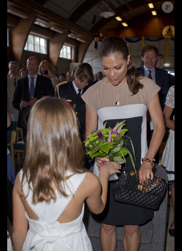 La princesse Victoria de Suède se voit offrir un bouquet de fleurs par une petite fille lorsqu'elle assiste à une commemoration pour le centenaire de la naissance de Raoul Wallenberg à Sigtuna le 4 août 2012