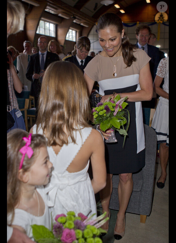 La princesse Victoria de Suède se voit offrir un bouquet de fleurs par une petite fille lorsqu'elle assiste à une commemoration pour le centenaire de la naissance de Raoul Wallenberg à Sigtuna le 4 août 2012