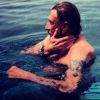 Laeticia Hallyday prend en photo son homme, Johnny, en train de profiter de la piscine de leur villa. Août 2012