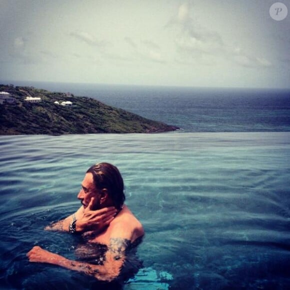 Laeticia Hallyday prend en photo son homme, Johnny, en train de profiter de la piscine de leur villa. Août 2012