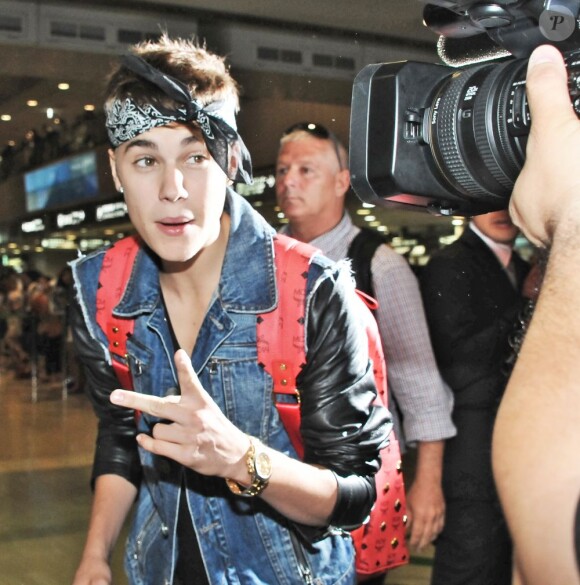 Justin Bieber, bandana noué sur le front et sac clouté MCM au dos à l'aéroport international de Narita. Tokyo, le 9 juillet 2012.