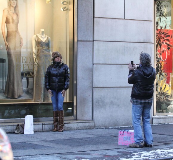 Kurt Russell prend en photo Goldie Hawn devant la vitrine d'une boutique qui présente un portrait géant de leur fille Kate Hudson, à New York, le 26 janvier 2013.