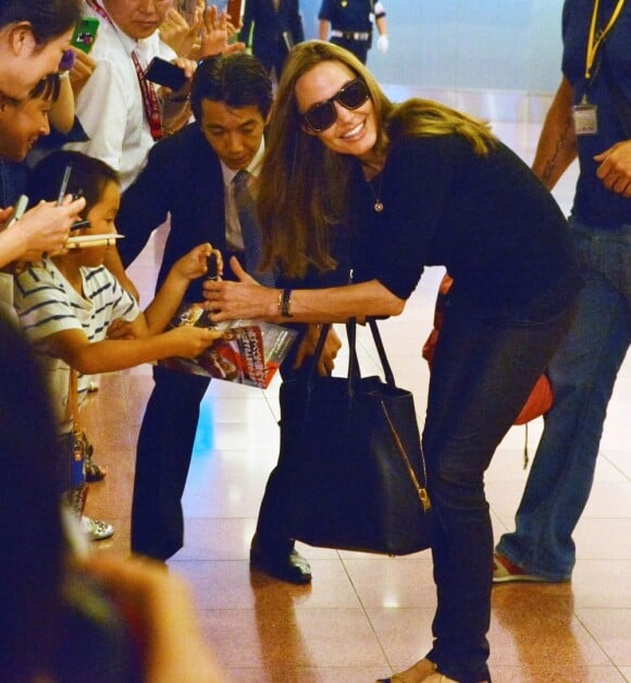 Brad Pitt et Angelina Jolie arrivant à l'aéroport de Tokyo-Haneda avec trois de leurs enfants, le 28 Juillet 2013. Angelina signe quelques autographes avec enthousiasme