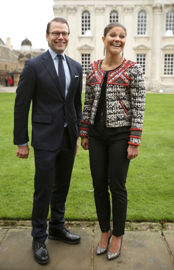 La princesse Victoria de Suède, souriante au côté de son mari le prince Daniel, porte une veste et des chaussures Isabel Marant pour H&M, avec un top et un pantalon noir. Cambridge, le 8 novembre 2013.