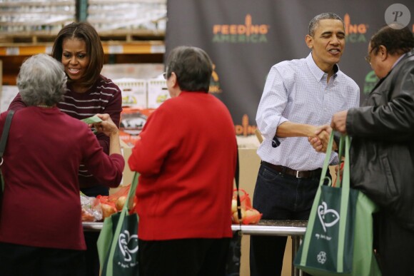 Barack Obama a distribué des colis de nourriture avec ses filles Malia et Sasha, ainsi que son épouse Michelle, dans les locaux de l'association Capital Area Food Bank à Washington, le 27 novembre 2013.