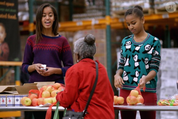 Barack Obama a distribué des colis de nourriture avec ses jolies filles Malia et Sasha, ainsi que son épouse Michelle, dans les locaux de l'association Capital Area Food Bank à Washington, le 27 novembre 2013.