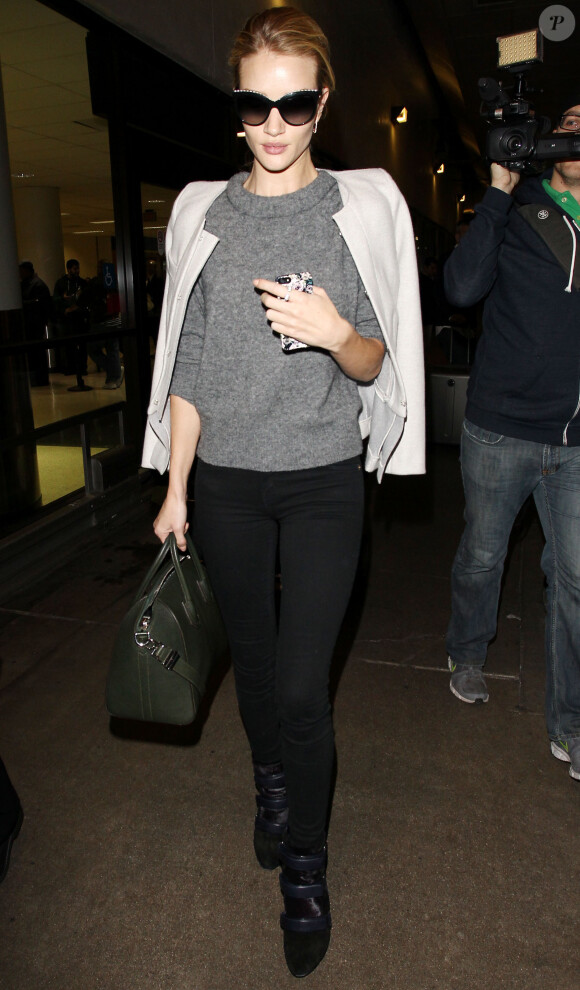 Rosie Huntington-Whiteley arrive à l'aéroport de Los Angeles, habillée d'une veste grise sans col, d'un sweater gris Isabel Marant Étoile, d'un jean noir et de bottines Isabel Marant (modèle Tacy). Des lunettes Chanel et un sac Givenchy (modèle Antigona) accessoirisent son look. Le 5 décembre 2013.