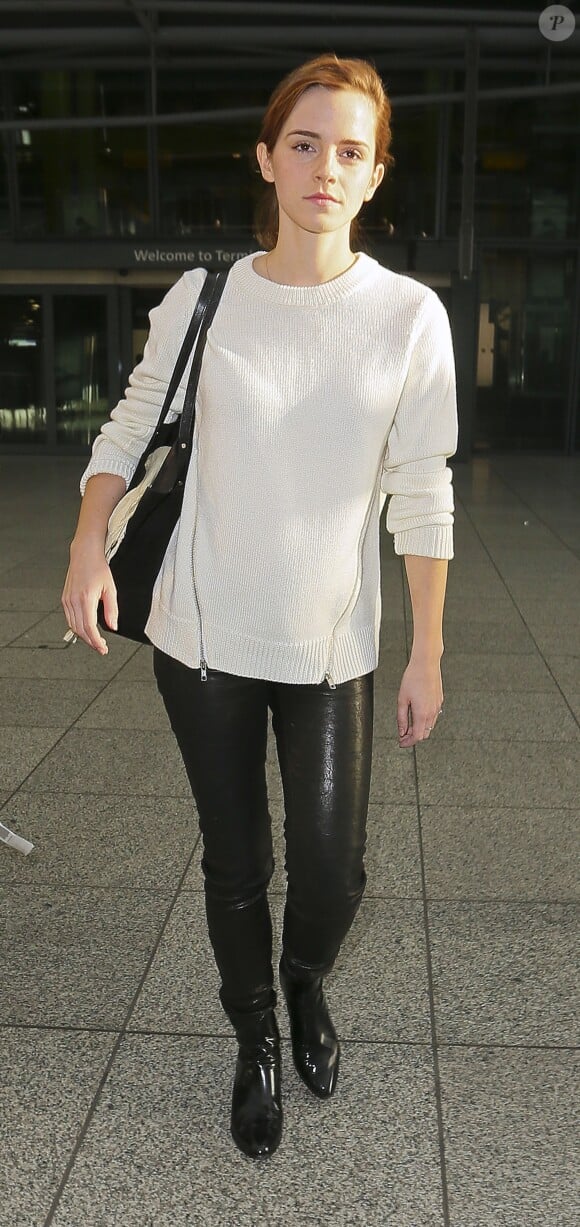 Emma Watson, surprise à l'aéroport d'Heathrow à Londres, porte un sweater blanc à zips Cut25 by Yigal Azrouël, un pantalon en cuir et des bottines 3.1 Phillip Lim (modèle Danny). Le 30 novembre 2013.