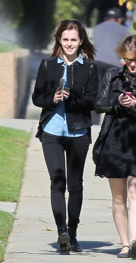 Emma Watson, souriante à Los Angeles, porte une veste Club Monaco (modèle Reid), une chemise A.P.C., un pantalon noir et des bottines 3.1 Phillip Lim (modèle Danny). Le 29 novembre 2013.