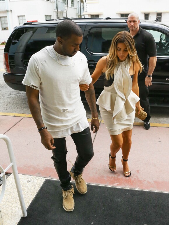 Kim Kardashian en pleine séance shopping à Miami avec Kanye West, porte une robe Givenchy (collection printemps-été 2012) sur un bustier en cuir Kiki de Montparnasse, une pochette dorée Bottega Veneta et des sandales Céline. Le 29 novembre 2013.