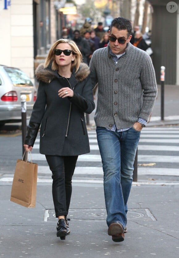 Reese Witherspoon fait du shopping à Paris avec son mari Jim Toth, habillée de Ray-Ban Wayfarer, un manteau Sandro (modèle Maddy), un pantalon et des bottines noires. Le 9 décembre 2013.