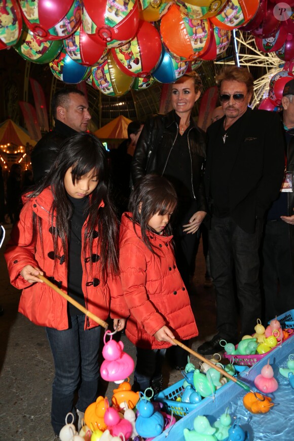 Johnny Hallyday, sa femme Laeticia et leurs filles Jade et Joy lors de la soirée d'inauguration de "Jours de Fêtes" au Grand Palais à Paris, le 19 décembre 2013. Les petites se sont amusées à la pêche aux canards.