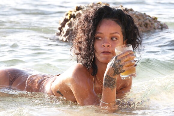 Rihanna boit une bière bien fraîche au bord de l'eau lors de ses vacances à la Barbade, le 28 décembre 2013.