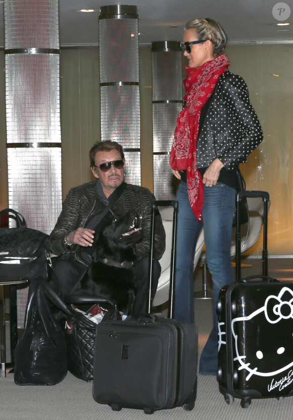 Johnny Hallyday et Laeticia Hallyday à l'aéroport de Roissy-Charles de Gaulle pour prendre un avion direction Los Angeles, le 12 janvier 2014.