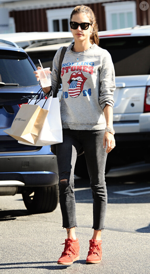 Alessandra Ambrosio, radieuse sous le soleil de Brentwood à Los Angeles, porte des lunettes de soleil Westward Leaning, un pull à l'effigie des Rolling Stones, un jean J Brand et des baskets Isabel Marant (modèle Bobby). Le 25 Janvier 2014.