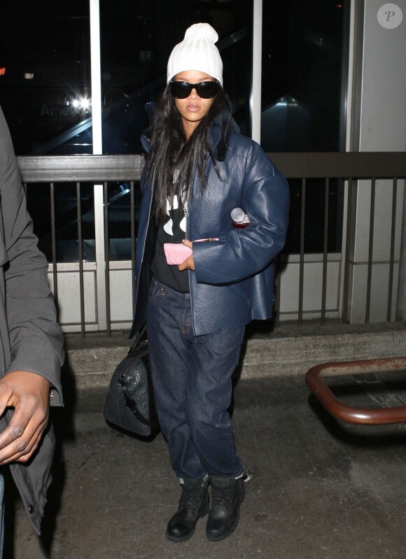 Rihanna arrive à l'aéroport de Los Angeles, habillée d'une veste Acne (modèle Major Dark Shale), d'un sweat à capuche Another Enemy, d'un jean brut Marni, de bottines Timberland et d'un sac Givenchy (modèle Antigona en croco). Le 30 janvier 2014.