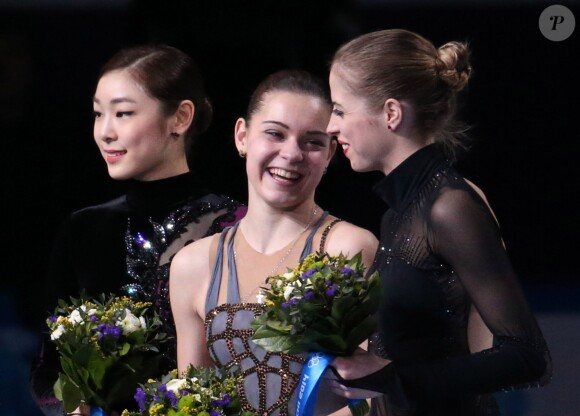Adelina Sotnikova entourée de la Sud-Coréenne Kim Yu-na et l'Italienne Carolina Kostner sur le podium des Jeux olympiques de Sotchi le 20 février 2014 à l'Iceberg Skating Palace de Sotchi