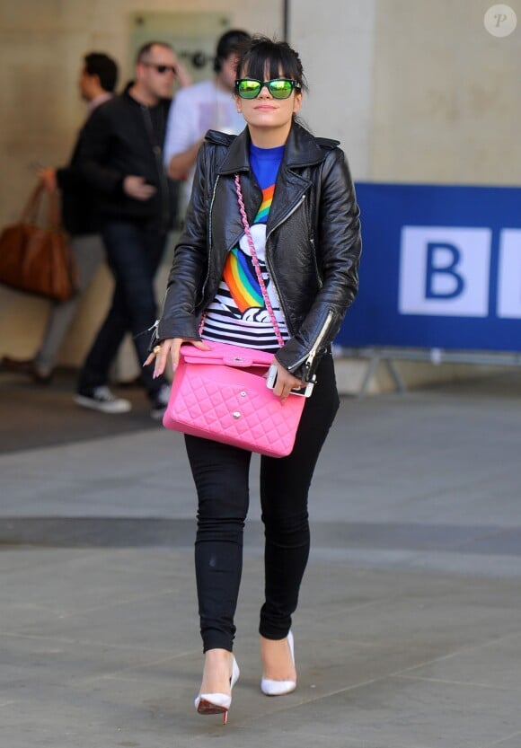 Lily Allen, aperçue à la sortie de BBC Radio One, porte un perfecto Balenciaga, un sweater Fay à l'effigie de Snoopy, un sac rose Chanel, un slim noir et des souliers Christian Louboutin. Londres, le 16 avril 2014.